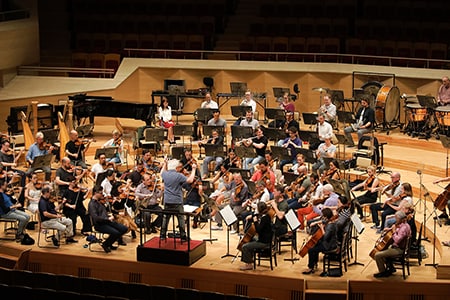 Orchestra members wear casual clothes for the rehearsal.
